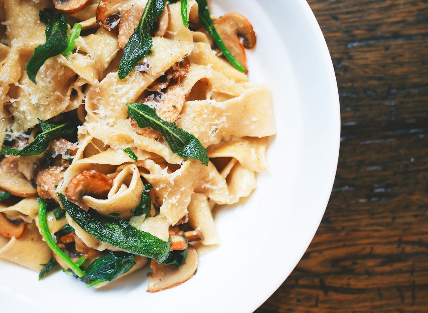 Pasta with spinach, mushrooms, and Parmesan on a rustic table